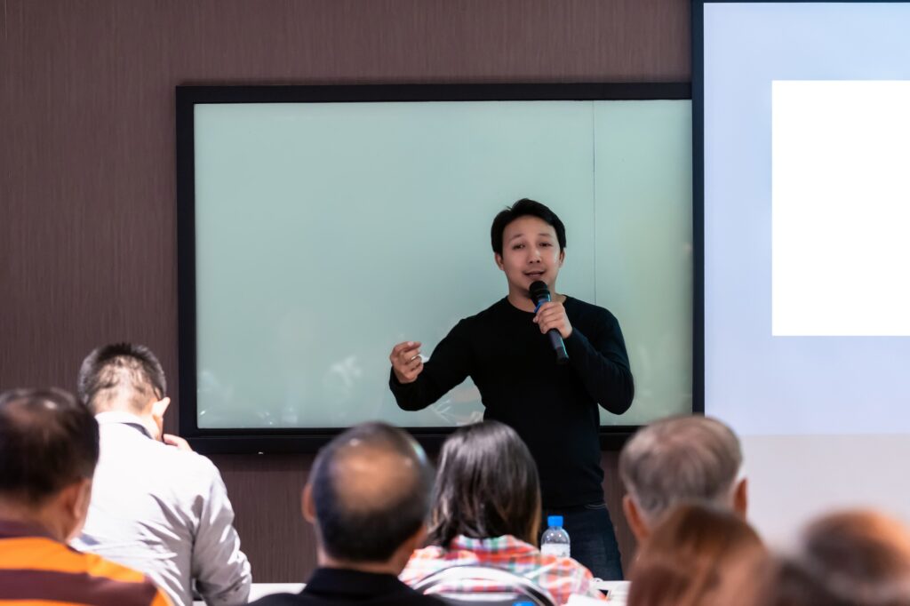 Asian Speaker or lecture with casual suit on the stage in front of the room presenting